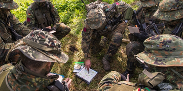 Ein Gruppe Fallschirmjäger der Reserve kniet über einer Karte und der Gruppenführer zeigt darauf.